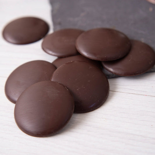 Dark chocolate buttons on a white surface