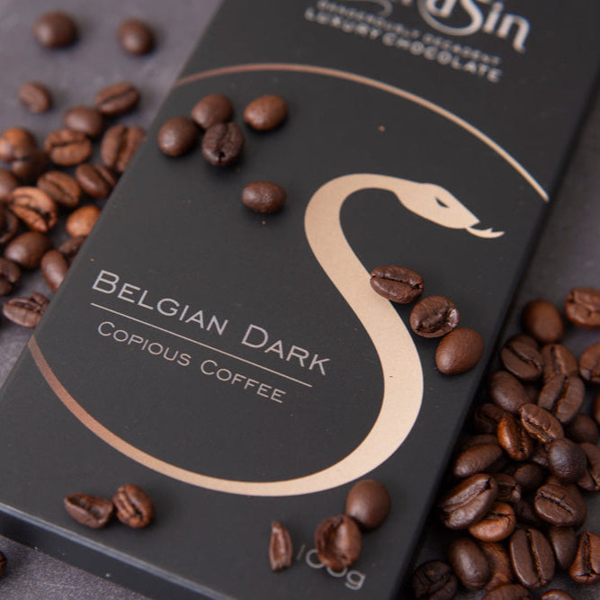 Belgian dark chocolate bar with coffee beans on a gray surface