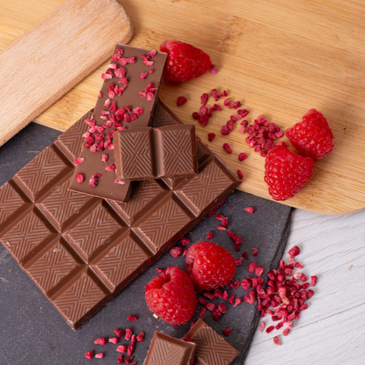 Chocolate bars with raspberries on a wooden board