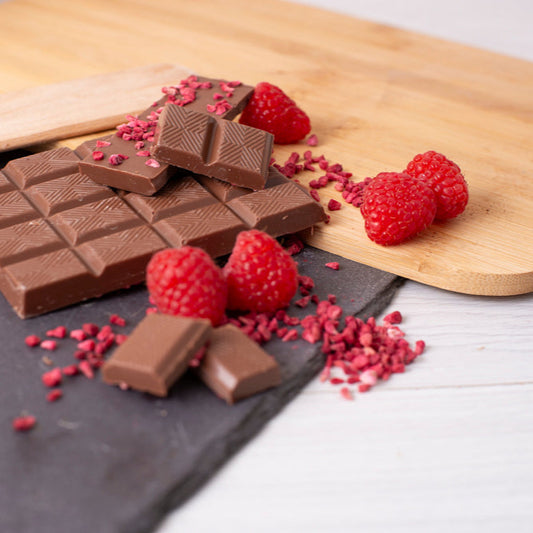 Chocolate bars with raspberries on a wooden cutting board