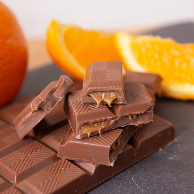 Chocolate bars with orange slices on a dark surface