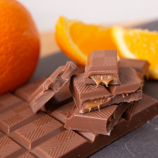 Chocolate bars with orange slices on a dark surface
