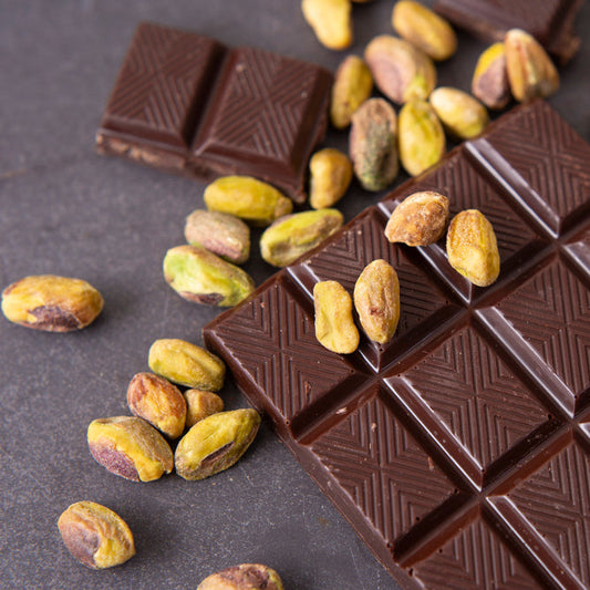 Dark chocolate bars with pistachios on a dark surface