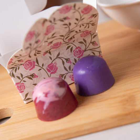 Purple chocolate truffles on a wooden board with a floral card