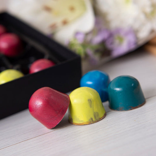 Colorful chocolate truffles on a white surface with a blurred background