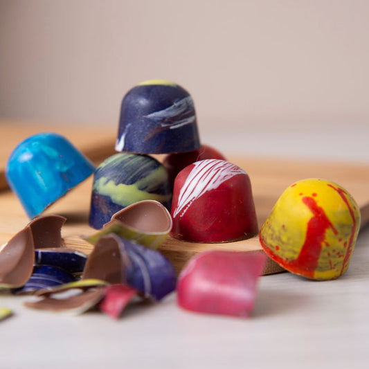 Colorful chocolate truffles on a wooden board with a neutral background