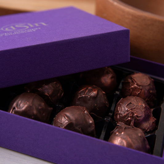 Purple box of chocolates with 'thirdsin' branding on a wooden surface.