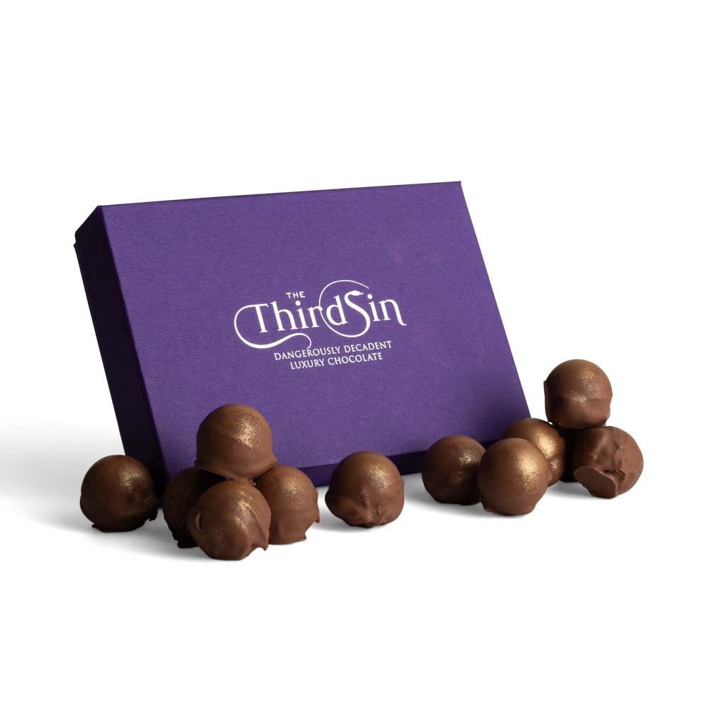 Chocolate truffles in front of a purple box with 'The Third Sin' branding on a white background
