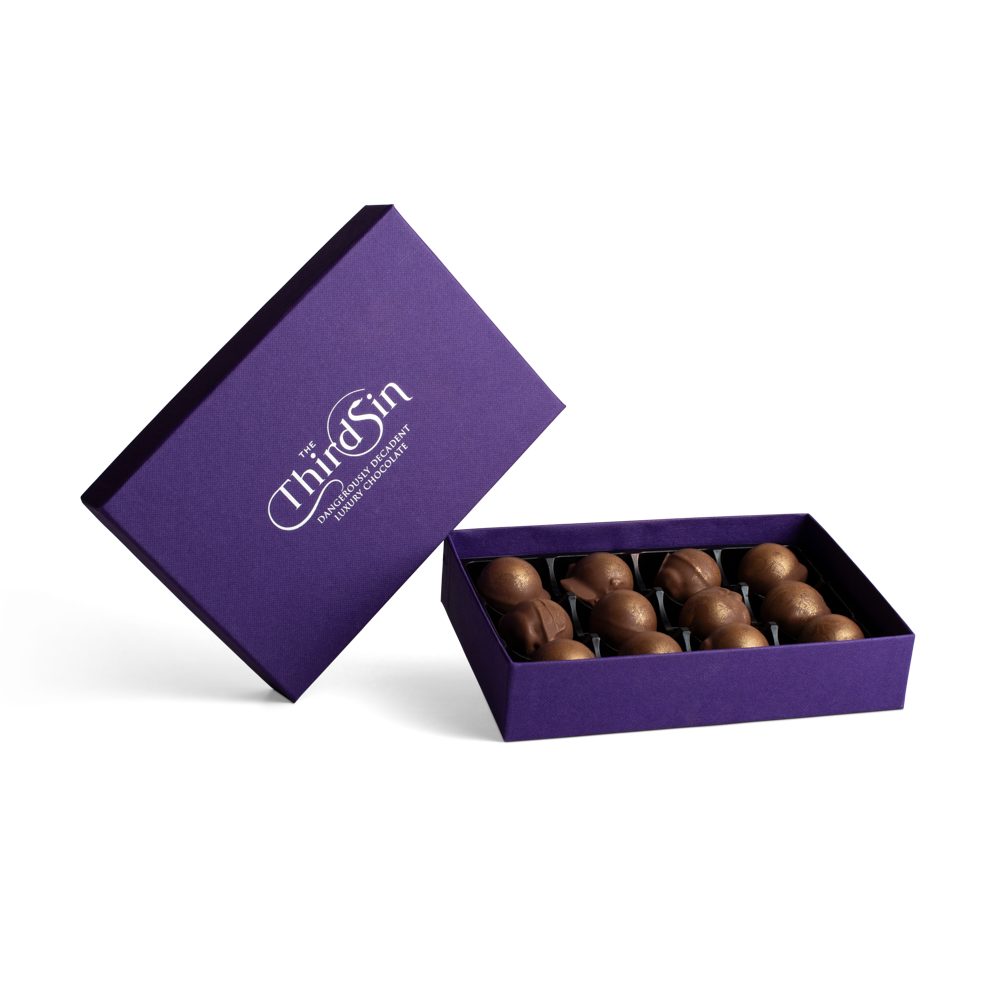 Open purple box with chocolates and 'The Third Sin' branding on a white background