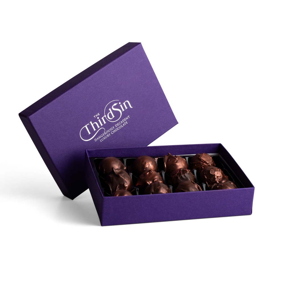 Open purple box containing chocolate figurines with 'The Third Sin' branding.