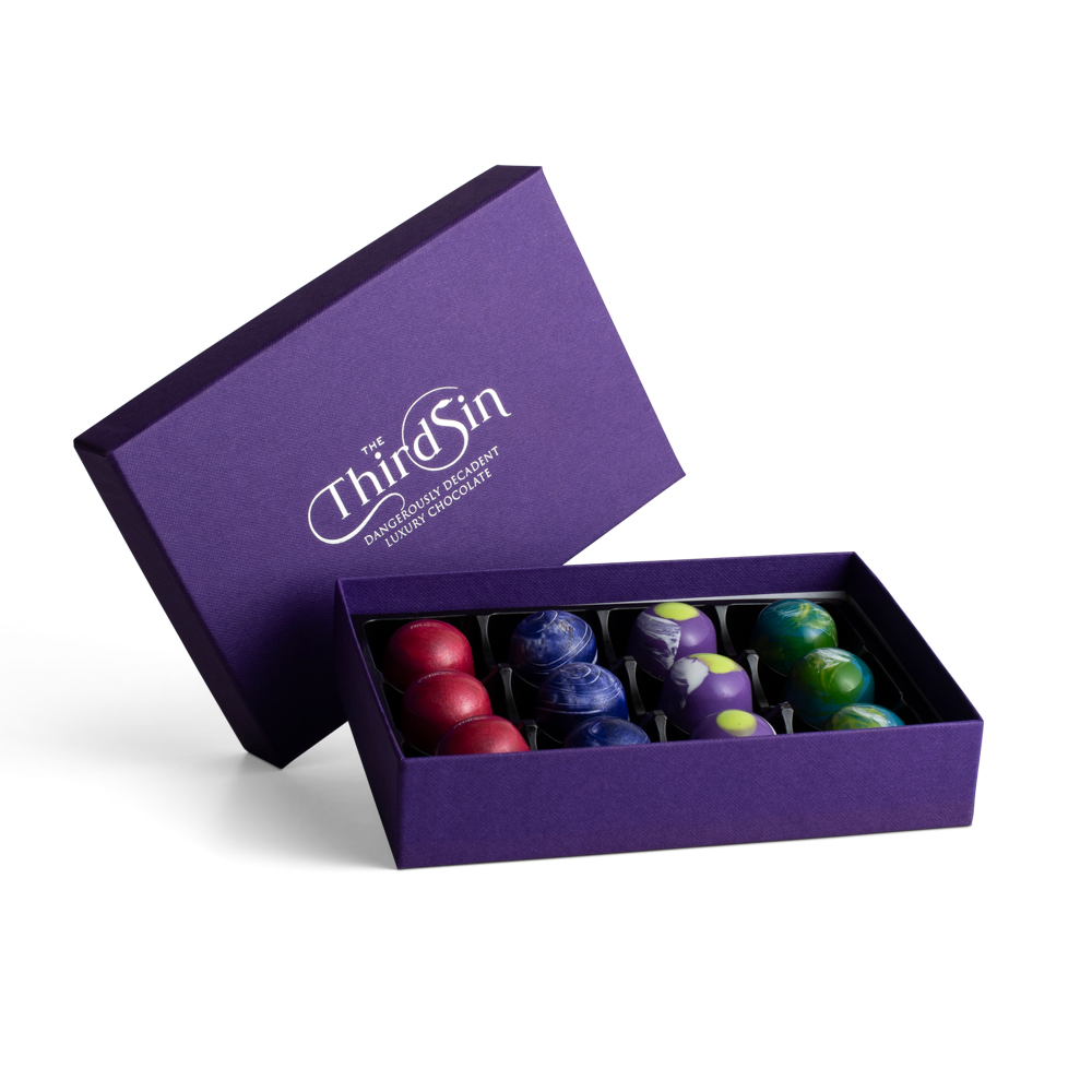 Purple box with 'The Third Sin' branding containing colourful chocolates on a white background