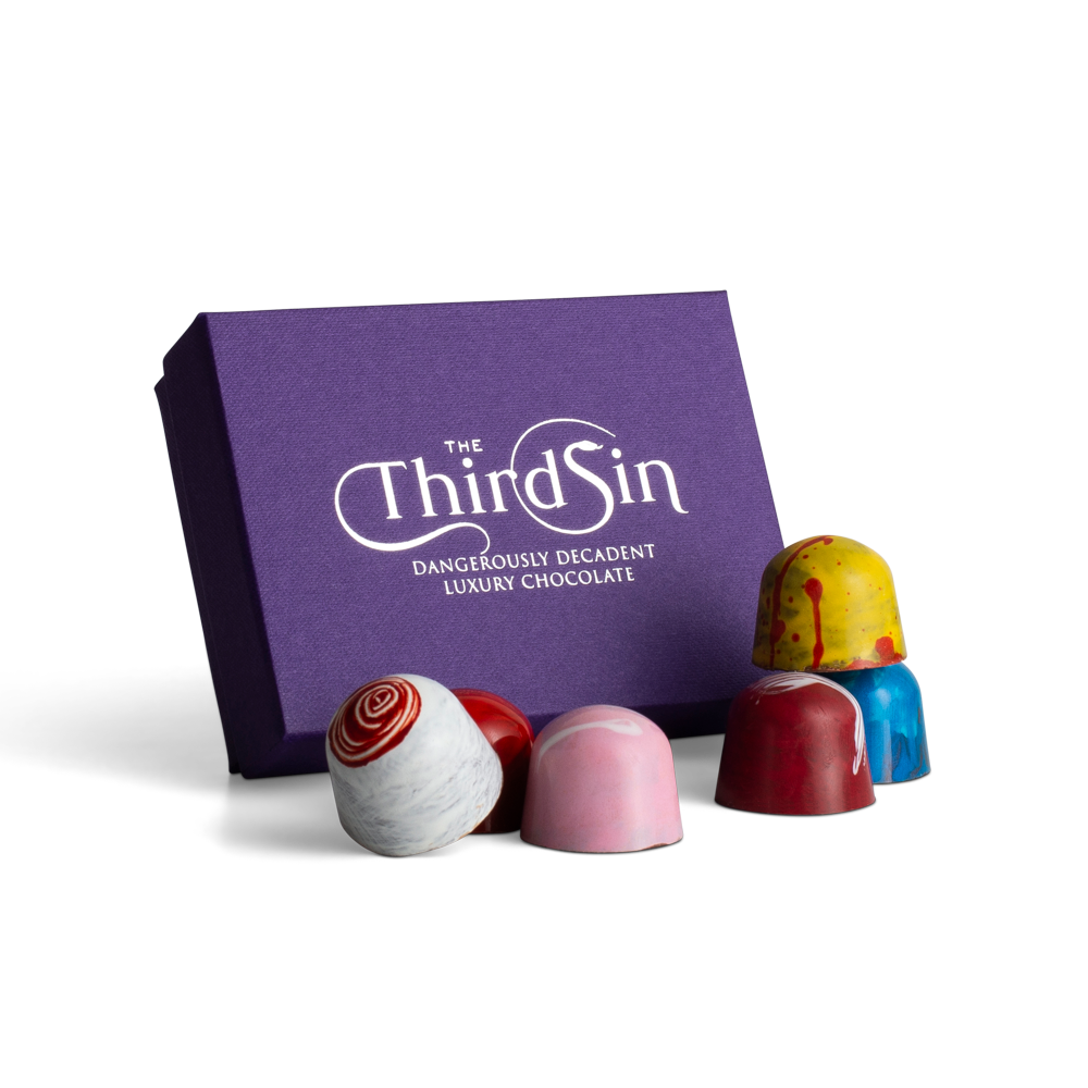 Colorful chocolate in front of a purple 'The Third Sin' box on a white background