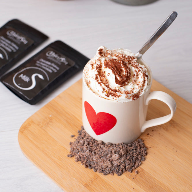 Hot chocolate with whipped cream and a heart-shaped design on a wooden board.