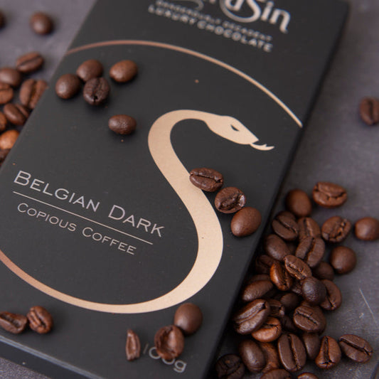 Belgian dark chocolate bar with coffee beans on a gray surface