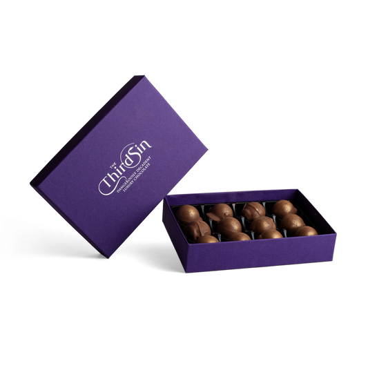Open purple box with chocolates and 'The Third Sin' branding on a white background