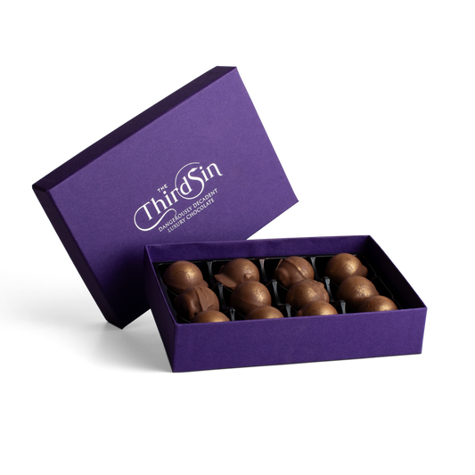 Open purple box of chocolates with 'The Third Sin' branding on a white background